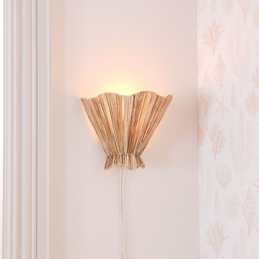 Close view of Ellara raffia wall light glowing on the wall