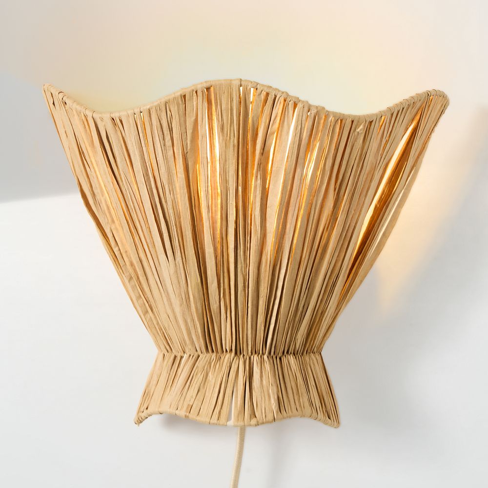 Ellara raffia wall light illuminated and fully visible on a plain wall