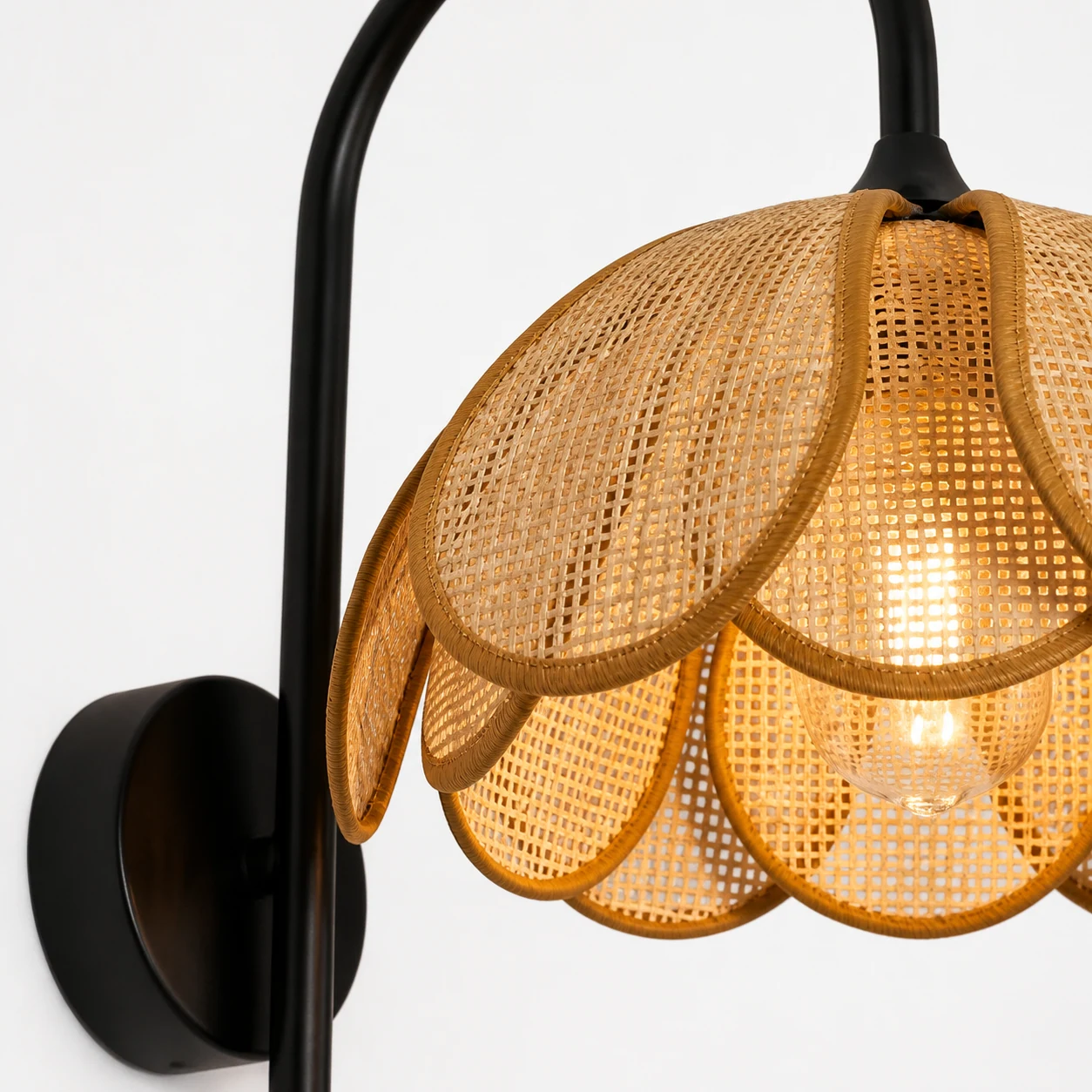 Close-up material detail of the woven rattan flower shade and black metal construction