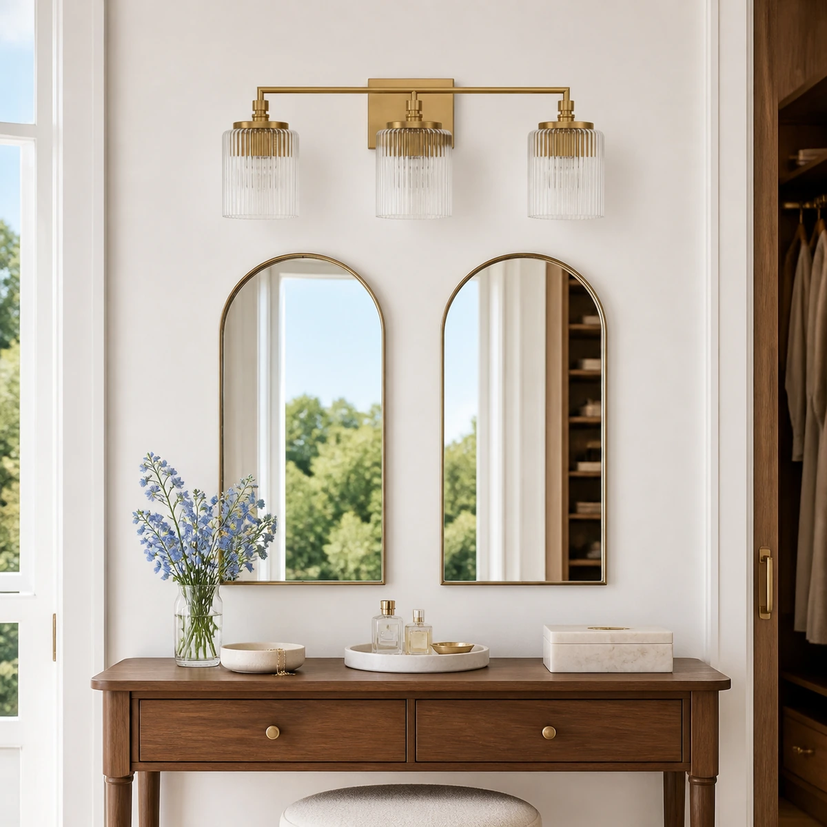 Satin Brass Serel wall sconce above two arched dressing mirrors
