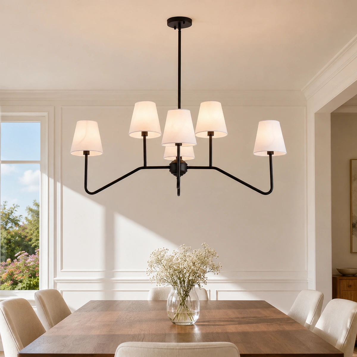 Lustre incurvé à six têtes en fer noir avec abat-jour en lin blanc dans une salle à manger baignée de soleil