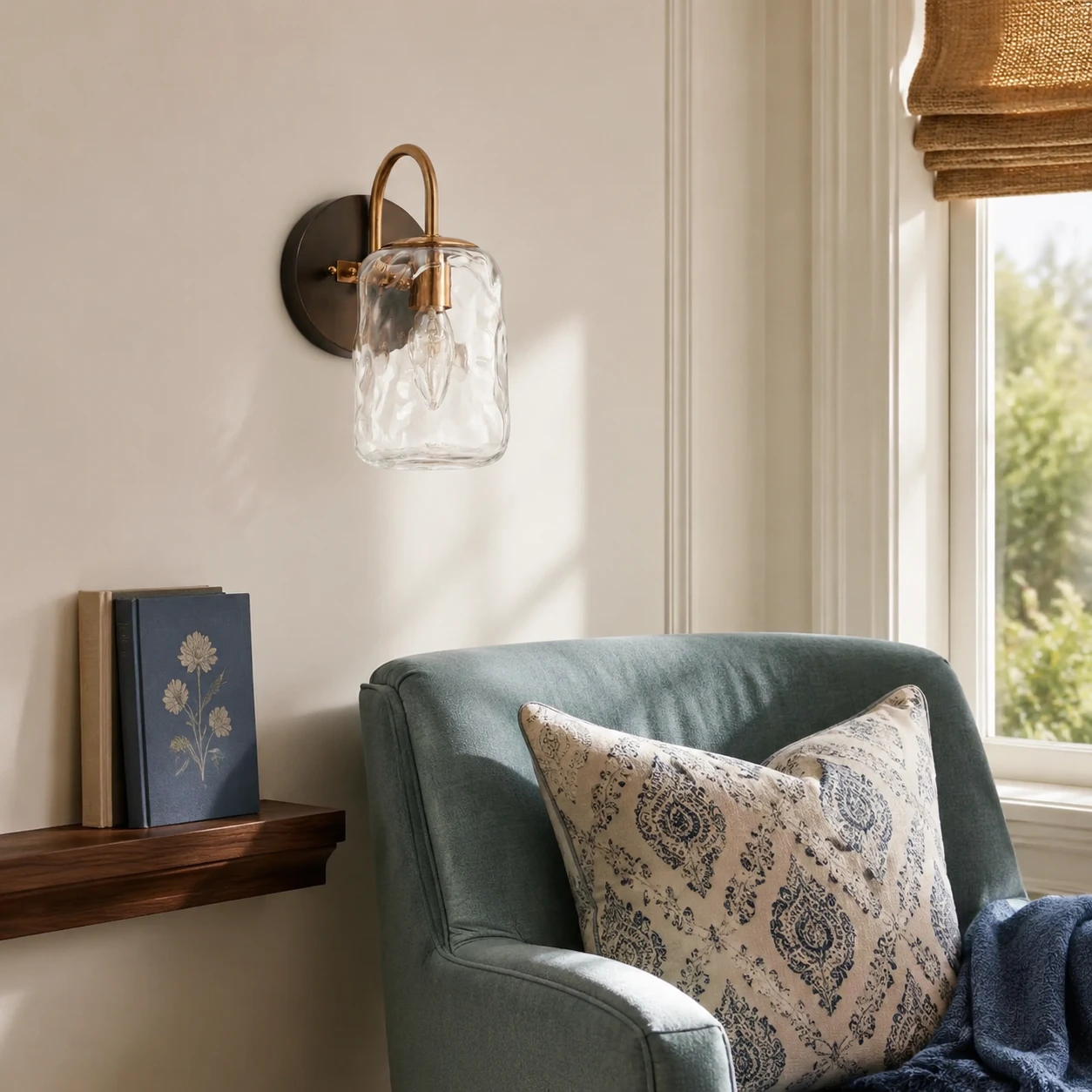 One-light Blythe wall sconce beside a teal reading chair in daylight