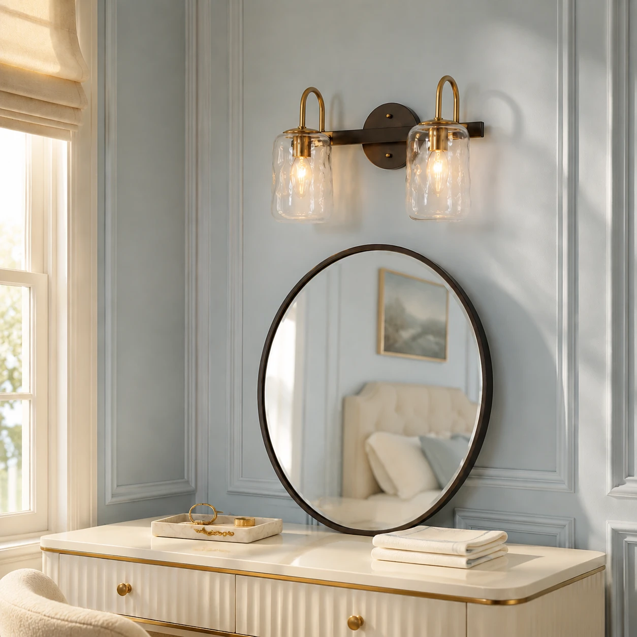 Two-light Blythe wall sconce above an oval mirror in a sunlit blue dressing area