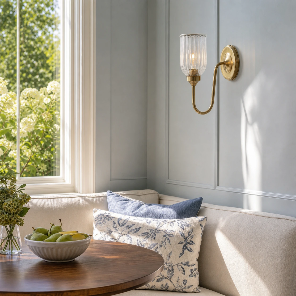 Menae Antique Brass wall sconce in a sunlit breakfast alcove