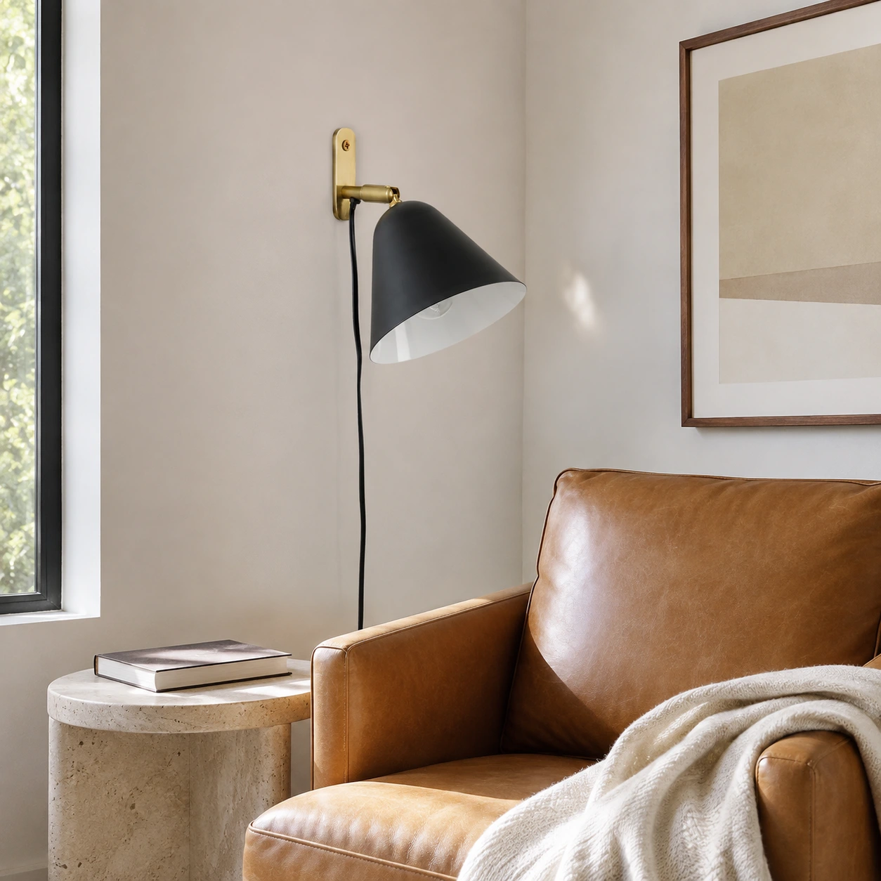 Matte Black Phrike wall sconce beside a leather reading chair